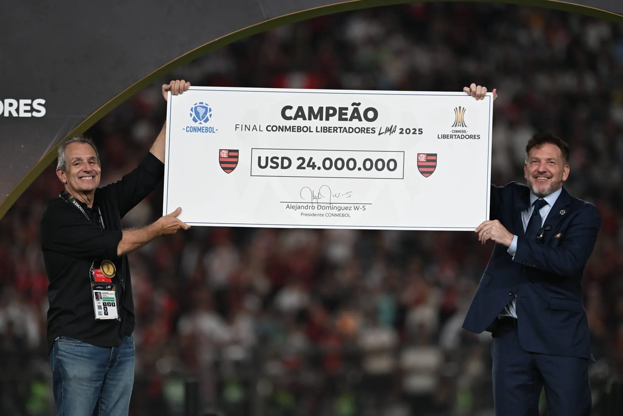 BAP, presidente do Flamengo, e Alejandro Dom&iacute;nguez, presidente da Conembol, erguem o cheque de campe&atilde;o da Libertadores 2025 