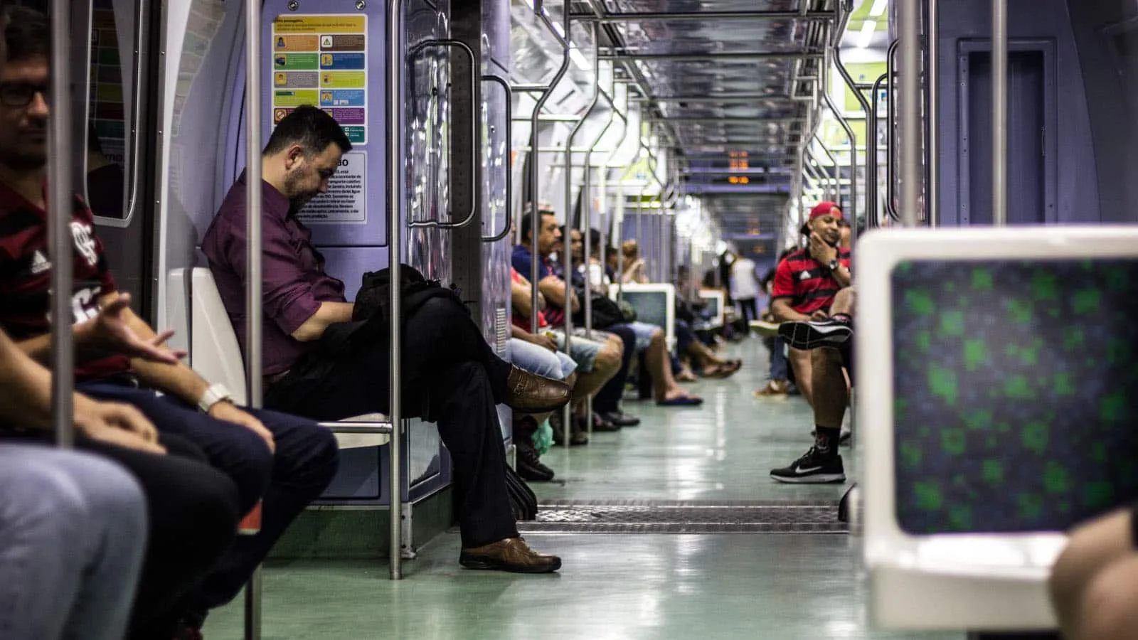 Trem com pessoas sentadas e o corredor vazio