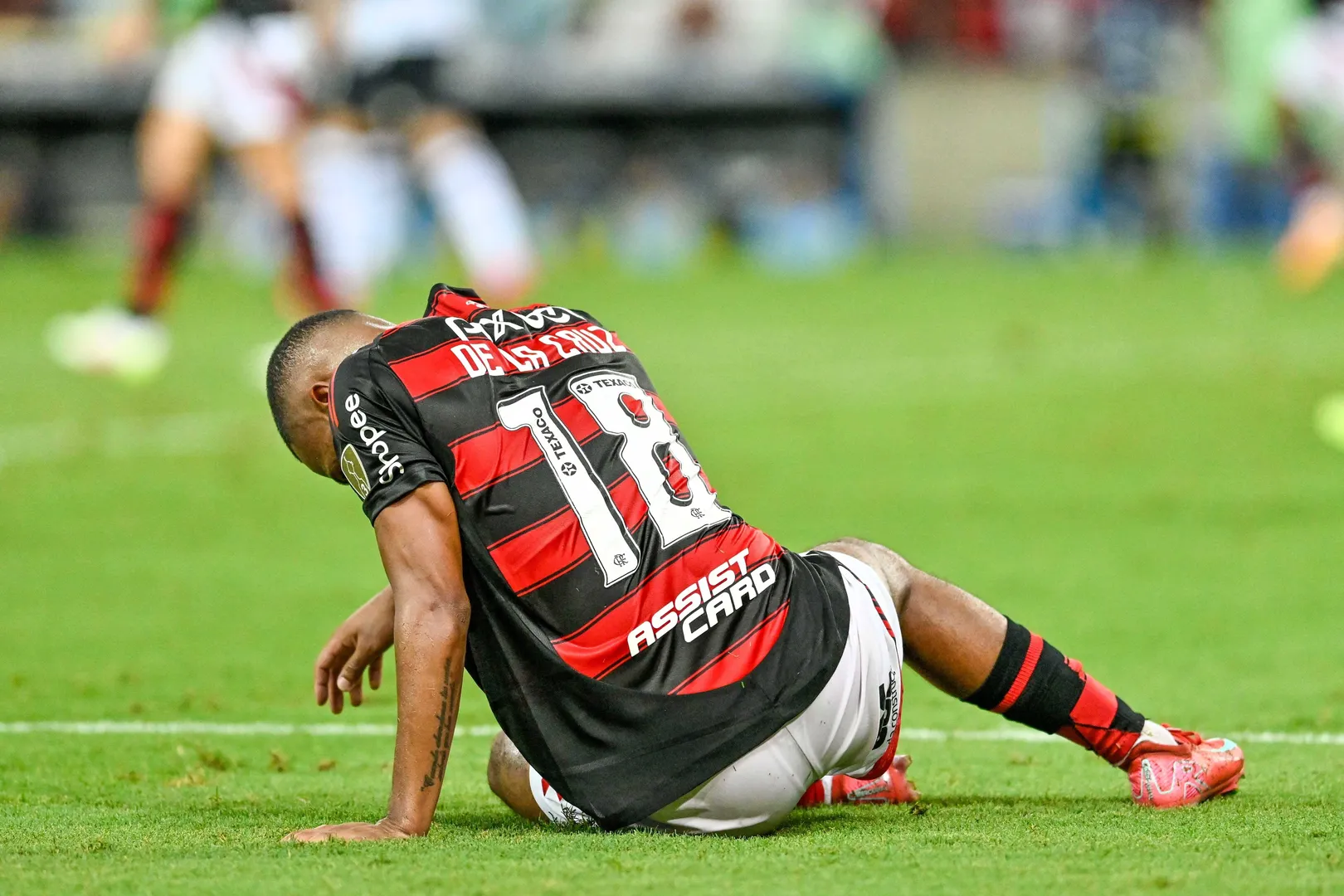 De la Cruz ca&iacute;do no gramado durante jogo do Flamengo