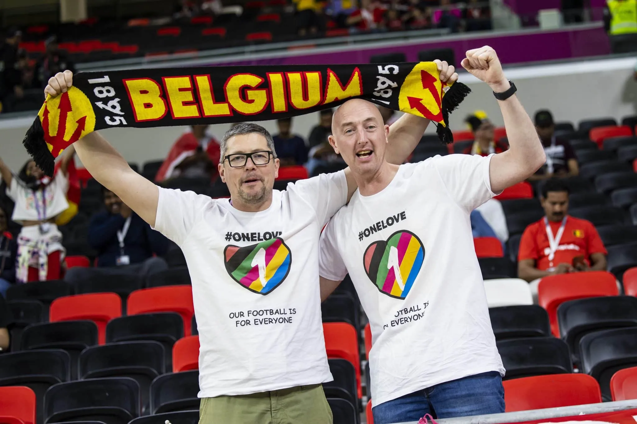 Torcedores belgas seguram um cachecol em jogo da Copa do Mundo no Catar e vestem camisetas com a inscri&ccedil;&atilde;o One Love
