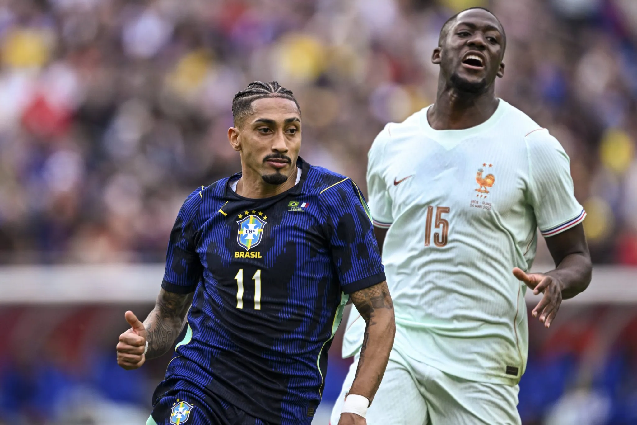 Raphinha disputa a bola com Konat&eacute; em amistoso entre Brasil e Fran&ccedil;a