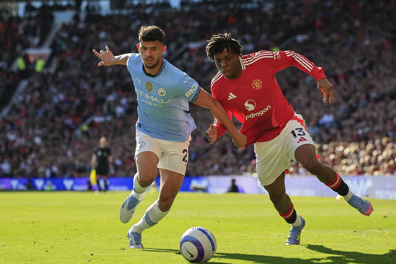 Patrick Dorgu em disputa de bola com Matheus Nunes em United x City