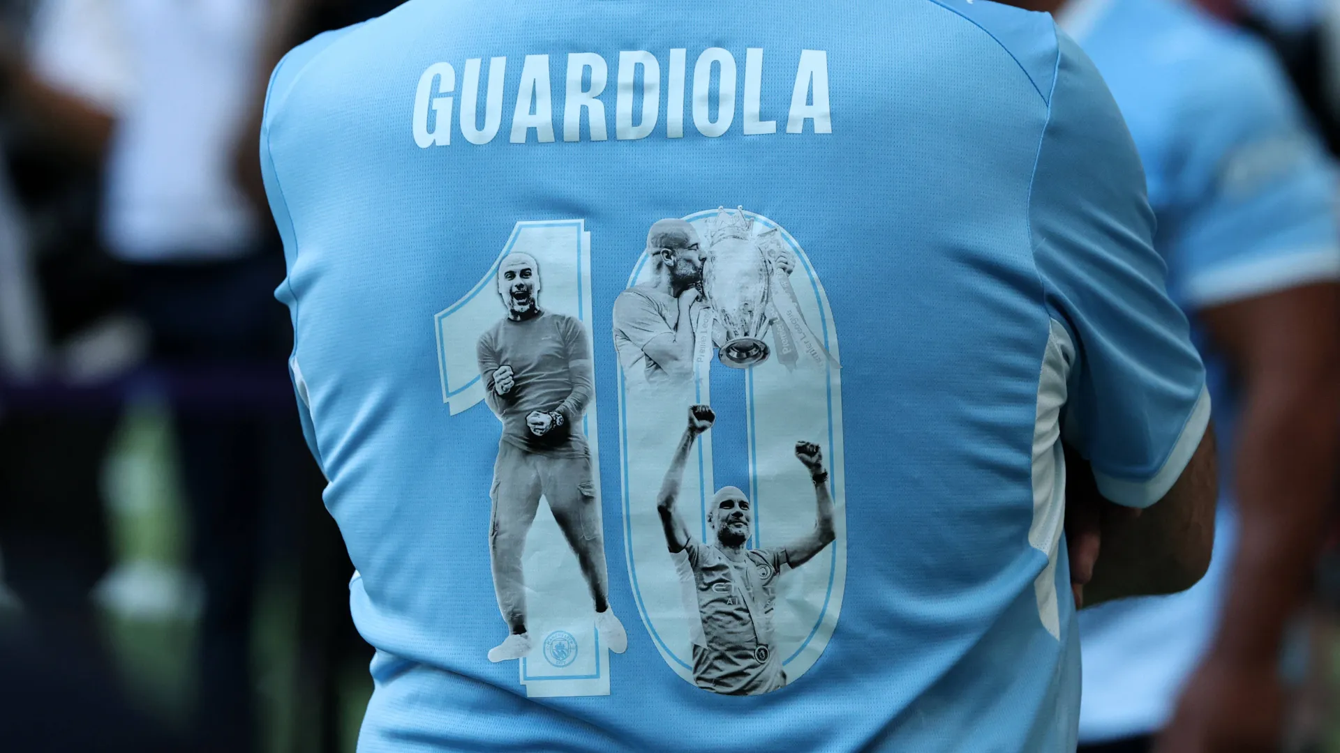 Torcedor do Manchester City usando uma camisa comemorativa pelos dez anos de Pep Guardiola no clube, durante a partida da Premier League contra o Aston Villa, no Etihad Stadium, em Manchester, na Inglaterra, em 24 de maio de 2026.